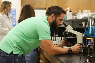 Male student looking through microscope